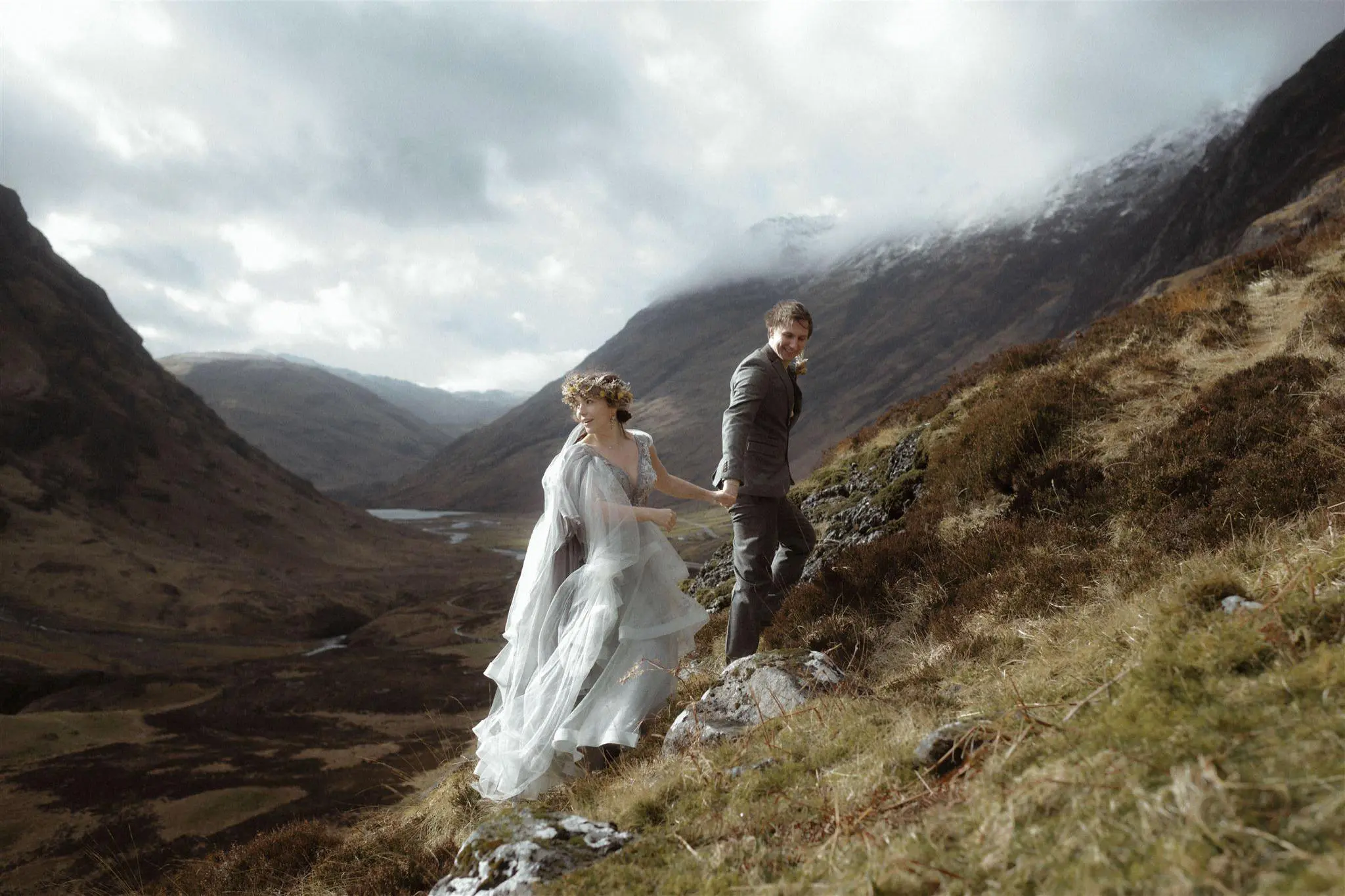 A groom leads a bride up a hillside in Glencoe after their Glencoe elopement