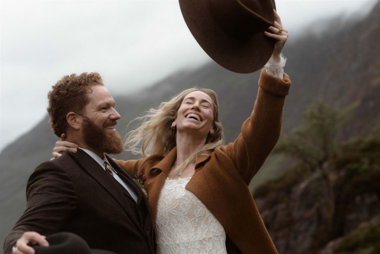 A bride and groom celebrate their Scottish elopement waving their cowboy hats in the air