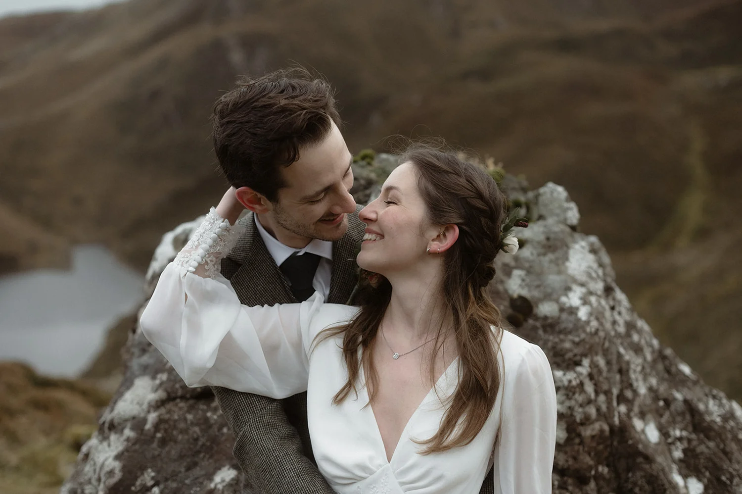 An eloping couple lean back on a rock with the bride resting her back on her new husband